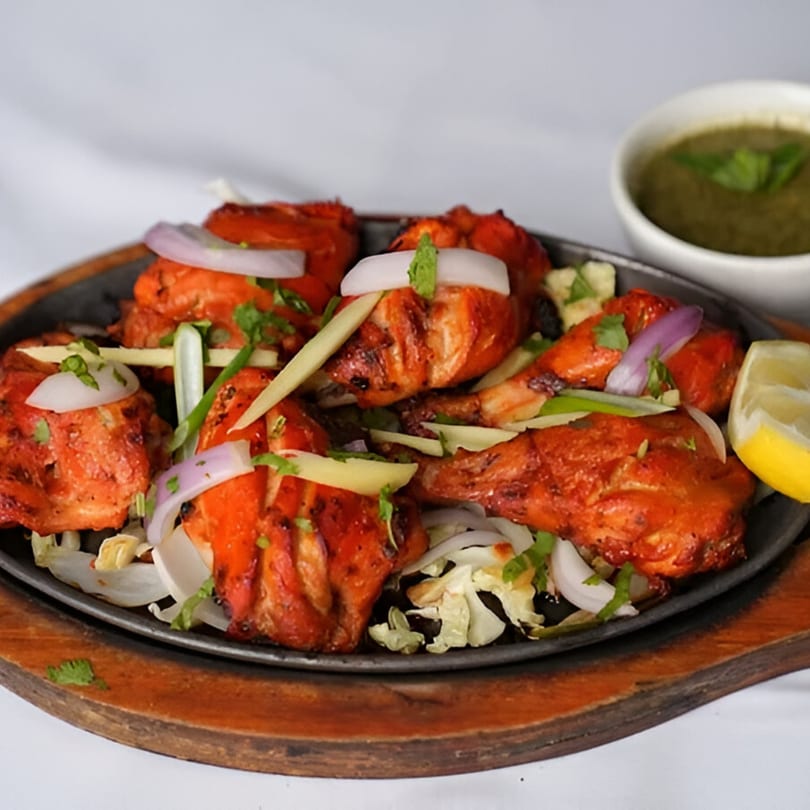 Nanking Indian Restaurant's Tandoori Chicken, garnished with onions, ginger, and cilantro, served with green chutney.